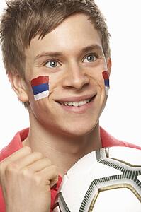 Young Male Football Fan With Serbian Flag Painted On Face