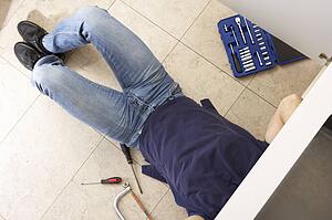 Plumber Working On Sink In Kitchen