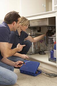 Plumber Teaching Apprentice To Fix Kitchen Sink In Home