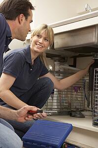 Plumber Teaching Apprentice To Fix Kitchen Sink In Home