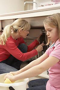 Daughter Helping Mother To Mop Up Leaking Sink