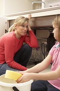 Daughter Helping Mother To Mop Up Leaking Sink
