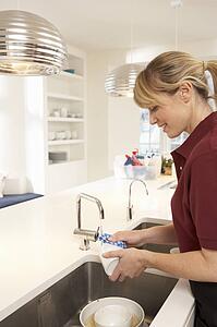 Cleaner Working In Domestic Kitchen