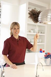 Cleaner Working In Domestic Kitchen With Feather Duster