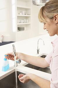 Woman Washing Hands At Kitchen Sink