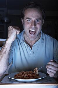Man Enjoying Meal And Cheering Whilst Watching TV