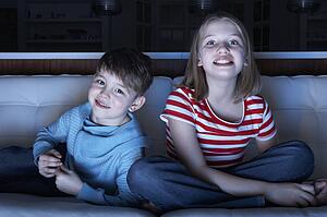 Children Watching TV Together Sitting On Sofa