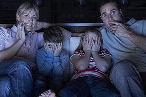 Family Watching Scary Programme On TV Sitting On Sofa Together