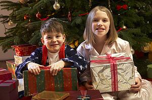 Children Opening Christmas Present In Front Of Tree