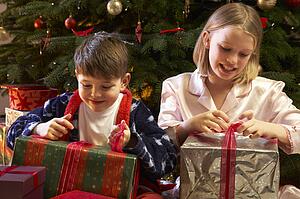 Children Opening Christmas Present In Front Of Tree