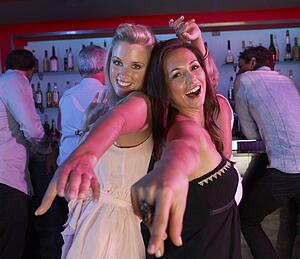 Two Young Women Having Fun In Busy Bar