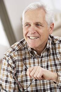 Senior Man With Glasses Relaxing In Chair At Home