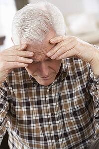 Senior Man Looking Stressed In Chair At Home