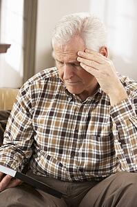 Sad Senior Man Looking At Photograph In Frame