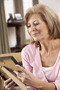 Senior Woman Looking At Photograph In Frame