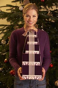 Woman Holding Christmas Gifts In Front Of Tree