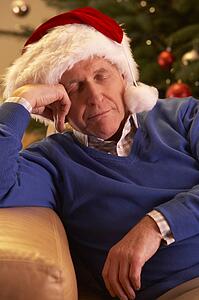 Tired Senior Man Relaxing In Front Of Christmas Tree