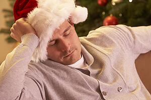 Tired Man Relaxing In Front Of Christmas Tree
