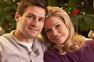 Couple Relaxing In Front Of Christmas Tree