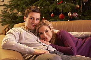 Couple Relaxing In Front Of Christmas Tree