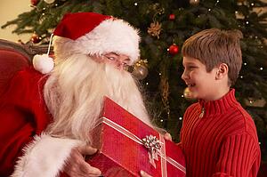 Santa Claus Giving Gift To Boy In Front Of Christmas Tree