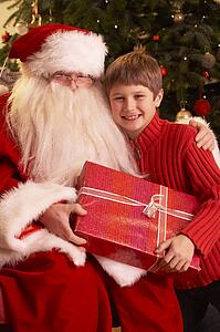 Santa Claus Giving Gift To Boy In Front Of Christmas Tree