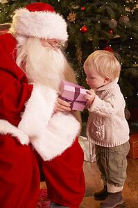 Santa Claus Giving Gift To Boy In Front Of Christmas Tree