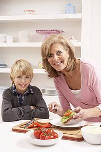 Grandmother And Grandson Making Sandwich In Kitchen
