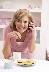 Senior Woman Enjoying Hot Drink Whilst On Phone
