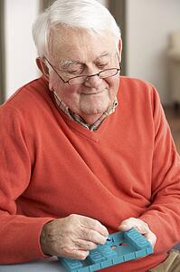 Senior Man Sorting Medication Using Organiser At Home
