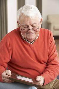 Senior Man Looking At Photograph In Frame