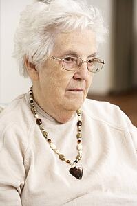 Senior Woman Looking Sad In Chair At Home