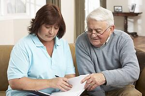 Senior Man In Discussion With Health Visitor At Home