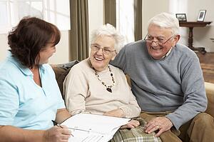 Senior Couple In Discussion With Health Visitor At Home