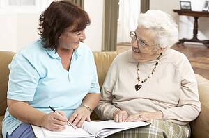 Senior Woman In Discussion With Health Visitor At Home