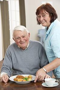 Senior Man Being Served Meal By Carer