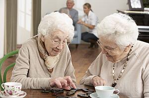 Two Senior Women Playing Dominoes At Day Care Centre