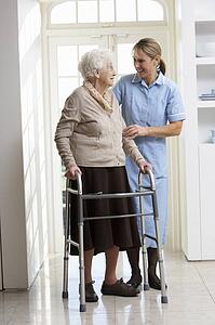 Carer Helping Elderly Senior Woman Using Walking Frame