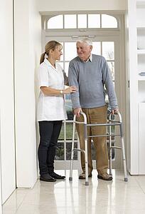 Carer Helping Elderly Senior Man Using Walking Frame
