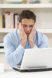 Worried Looking Man Working From Home Using Laptop