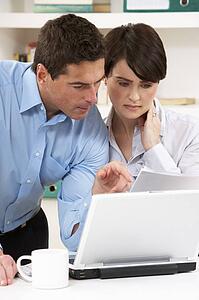 Worried Couple Working From Home Using Laptop