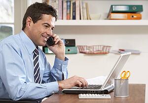 Man Working From Home Using Laptop On Phone
