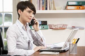 Woman Working From Home Using Laptop On Phone