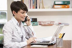Woman Working From Home Using Laptop On Phone