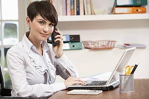 Woman Working From Home Using Laptop On Phone