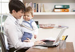 Woman With Baby Working From Home Using Laptop