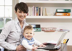 Woman With Baby Working From Home Using Laptop