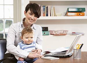 Woman With Baby Working From Home Using Laptop