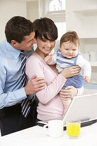 Parents With Baby Working From Home Using Laptop