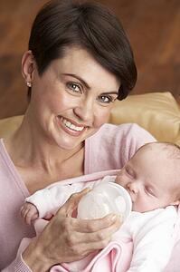 Portrait Of Mother Feeding Newborn Baby At Home